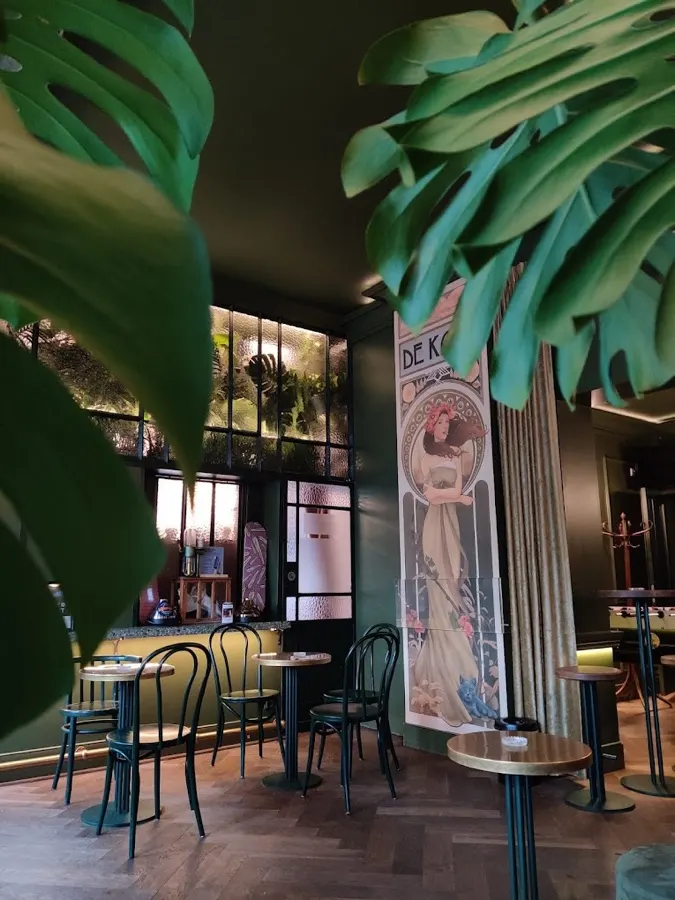 The De Kade interior with monstera leaves and an art nouveau mural